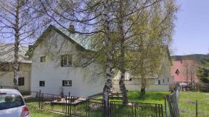 a white house with a tree and a fence at ApartmanMN in Žabljak