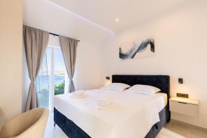 a white bedroom with a bed and a window at Stone house Mia in Čara