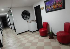 a waiting room with two red chairs and a tv at Hotel Nexo in Medellín +3 photos