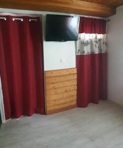 a room with red curtains and a flat screen tv at Studio dans mon chalet La Mère Veille in La Girard