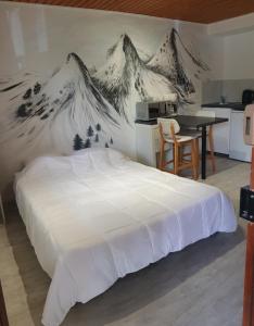 a bedroom with a bed with a mountain mural on the wall at Studio dans mon chalet La Mère Veille in La Girard