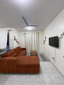a living room with a brown couch and a flat screen tv at cozy 1bedroom mombasa bamburi near the beach with hot shower, Netflix, Secured parking 07&07 for 95 then 61to18 in Mombasa