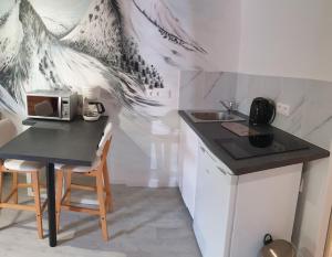 a small kitchen with a table and a microwave at Studio dans mon chalet La Mère Veille in La Girard