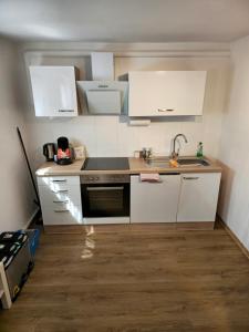 a small kitchen with white cabinets and a sink at Ruhige, modern eingerichtete 2 Zimmer Wohnung im Untergeschoss eines Zweifamilienhauses in Hildrizhausen +19 photos