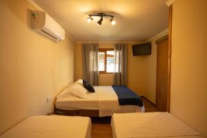 a small room with two beds and a tv at Maré Alta - Guest House in Ilha do Mel