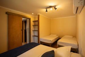 a small room with two beds and a closet at Maré Alta - Guest House in Ilha do Mel