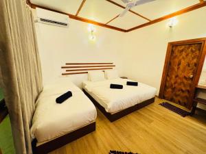two beds in a room with white sheets at Sevenseas Seaview Maldives in Feridhoo