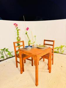 a wooden table with two chairs and a table with a plate at Sevenseas Seaview Maldives in Feridhoo