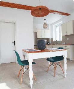 a kitchen with a white table and two green chairs at Hundred Noons in Khandrinós