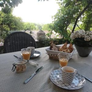 a table with plates and cups of coffee and a basket of food at La Villa Regula in La Réole +23 photos