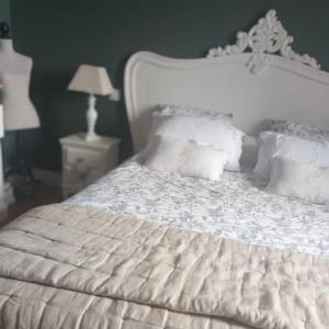 a white bed with white pillows and a night stand at La Villa Regula in La Réole