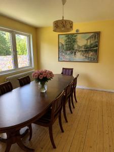 a dining room table with chairs and a vase of flowers at Villa Timsfors i Markaryd in Markaryd