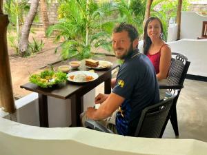 a man and a woman sitting at a table with food at Ceylon Salt & Soul in Arugam Bay