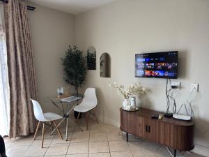 a living room with a table and a tv on the wall at The olive stay at Ocean view Villas F7 in Port Edward