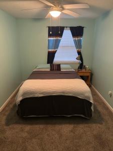 a bedroom with a bed with a ceiling fan and a window at Spacious cozy in Jacksonville