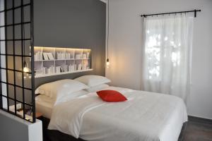 een slaapkamer met een wit bed met een rood kussen erop bij Piteoussa in Hydra