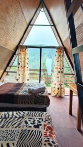 a room with a bed and a large window at Cabañas Ticomulco in Zacatlán