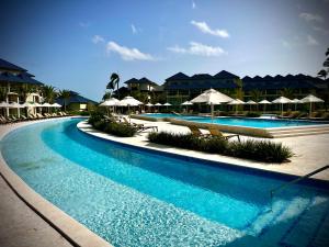 a pool with chairs and umbrellas in a resort at Xanadu Casa De La Playa in Puerto Plata