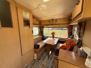 an interior view of an rv with a table and a couch at Hut 4 Ewe glamping pod with shared facilities in Bideford +23 photos