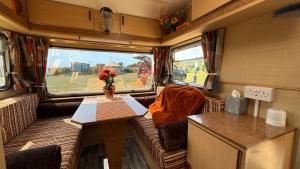 a living room with a table and a couch in an rv at Hut 4 Ewe glamping pod with shared facilities in Bideford