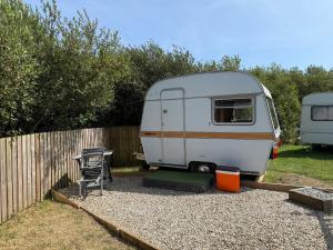 a white caravan parked next to a fence with a table at Hut 4 Ewe glamping pod with shared facilities in Bideford