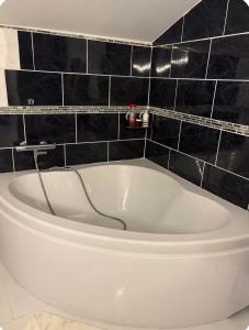a white bath tub in a bathroom with black tiles at Cécile Foissy in Pogny