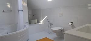 a white bathroom with a toilet and a sink at Apartman Romansa in Fojnica