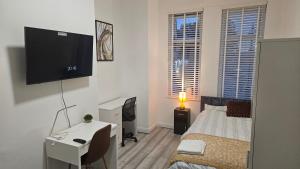 a bedroom with a bed and a desk and a television at New Horizon Lodge in Leigh