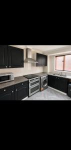 a kitchen with black cabinets and a sink and a dishwasher at 5, Casper Court in Nottingham