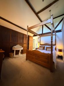 a bedroom with a wooden canopy bed and a piano at Braunston Manor Cottage in Braunston