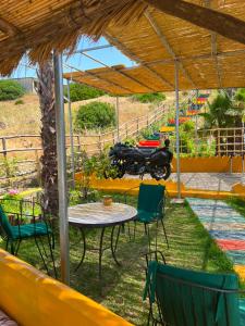 a table and chairs and a motorcycle parked under a pavilion at Auberge de Chez Momo in Asilah