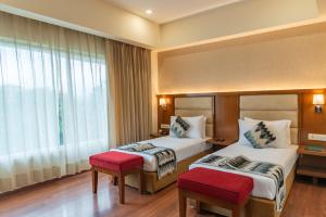 a hotel room with two beds and a window at Hotel Le Amritam in Dehradun +43 photos