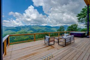 a deck with two chairs and a table with mountains in the background at Mtn-View 'Hidden Falls' Cabin w/ Hot Tub & Deck in Andrews