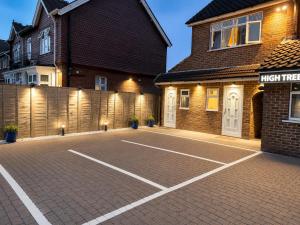 a parking lot in front of a house with a tennis court at High Trees Guest House Gatwick in Horley