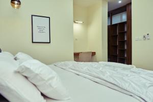 a bedroom with a bed with white pillows and a book shelf at Revkon Apartments in Abuja