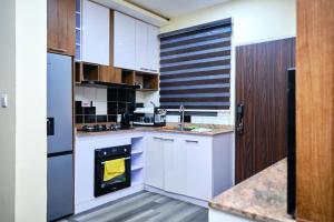 a kitchen with white cabinets and a sink and an oven at Revkon Apartments in Abuja
