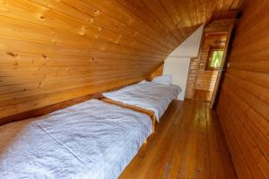 two beds in a room with wooden walls at Raj pod vrhom in Poljane nad Škofjo Loko