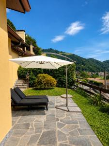 a patio with an umbrella and a couch and chair at Casa Gemelli in San Fedele Intelvi