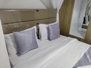 a white bed with three pillows and a mirror at Gee homestay Kakamega in Kakamega +3 photos