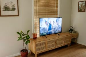 a flat screen tv sitting on top of a wooden entertainment center at Simple Style Among the Gums  +3 photos