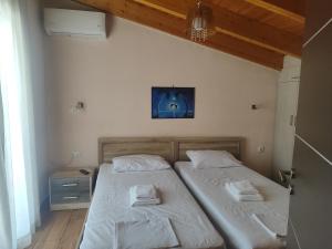 two twin beds in a bedroom with a tv on the wall at Maisonette Kalypso in Diakopto