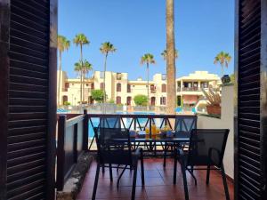 a table and chairs on a balcony with a view of a pool at STUDIO TAGORO in Costa Del Silencio