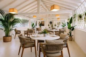 a dining room with tables and chairs and plants at Hotel Cala d'Oro - Hotel a pochi minuti dal mare di Cala Liberotto in Cala Liberotto