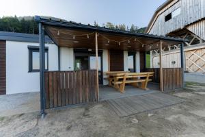 a wooden pavilion with a wooden picnic table and a bench at Hiška pod vrhom in Poljane nad Škofjo Loko +7 photos