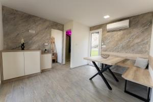 a dining room with a wooden table and a stone wall at Hiška pod vrhom in Poljane nad Škofjo Loko