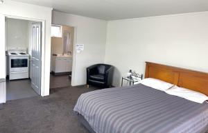 a bedroom with a bed and a chair in it at Charlton Motel in Gore