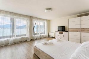 a white bedroom with large windows and a bed at Marso in Krašići