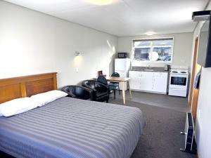 a bedroom with a bed and a table and chairs at Charlton Motel in Gore +7 photos