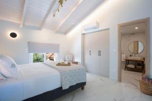 a white bedroom with a large bed and a mirror at Dante Home's in Corfu +2 photos