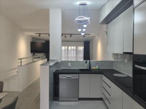 a kitchen with white cabinets and a black counter top at Apartmani Orlović Bar in Bar